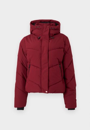 Rød puffjakke med hette, med en quiltet design, frontlommene med glidelås, og svarte mansjetter. Stoffet har en glatt, matt tekstur.