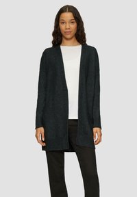 Dunkelgrauer gestrickter Cardigan mit offenem Vorderteil, langen Ärmeln und gerippten Bündchen. Über einem weißen T-Shirt getragen und mit schwarzen Hosen kombiniert.