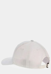 Casquette de baseball blanche avec une visière courbée, fermeture arrière ajustable et tissu texturé. Présente des coutures visibles et de légers signes d'usure.