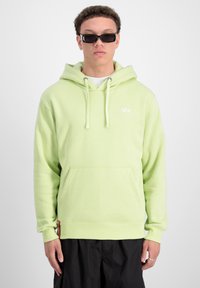 Felpa verde chiaro con tasca frontale, polsi a costine e cappuccio con cordino. Presenta un piccolo logo bianco sul petto e un'etichetta rossa.