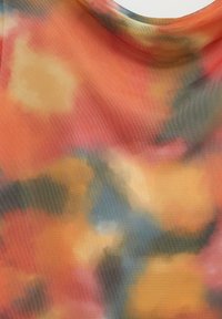 Tissu abstrait présentant un mélange de couleurs chaudes, y compris l'orange, le jaune et le bleu, avec une finition texturée et douce ainsi que des motifs subtils.