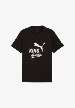 Juoda trumpomis rankovėmis marškinėliai su baltu Puma logotipu virš teksto „KING“ ir „Austria“ priekyje, ir mažas pleistras kairėje rankovėje.