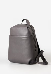 Zaino in pelle grigia con una superficie liscia e testurizzata. Presenta una chiusura con zip superiore e una tracolla regolabile. Design minimalista con una tasca frontale.