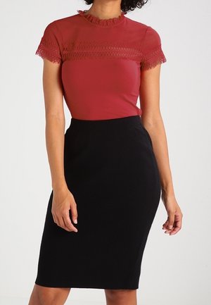 Mujer con una camiseta roja ajustada de manga corta con ribete de encaje y una falda lápiz negra de cintura alta hasta la rodilla.