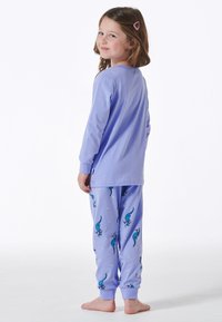 Lila langärmeliger Pyjama-Oberteil mit Rundhalsausschnitt, kombiniert mit passenden lila Schlafhosen, die ein verspieltes Dinosaurier-Muster und kontrastierende Bündchen aufweisen.