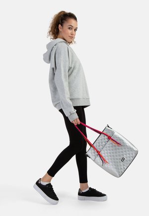 Grå oversized hoodie, sorte leggings og sorte sneakers. Metalisk sølvfarvet quiltet tote bag med pink og gule stropper.