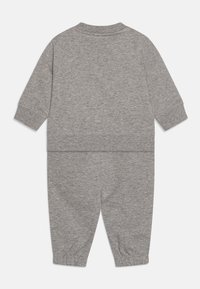 Completo grigio chiaro in due pezzi realizzato in cotone morbido. Caratterizzato da una maglia a maniche lunghe e pantaloni elasticizzati con polsini e vita a coste.