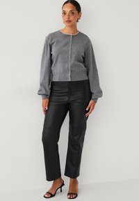Grå strikket cardigan med perle-lignende knapper, ballonsleeves, mikset med sorte læderbukser, som har en lige pasform og glat tekstur.