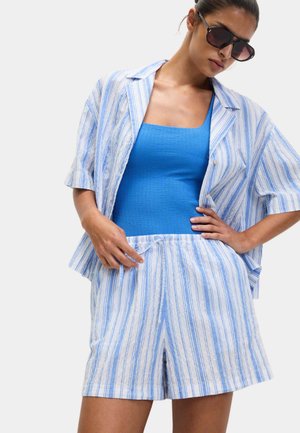 Camicia a righe in blu chiaro e bianco con maniche corte, abbinata a una canotta blu e pantaloni corti a righe coordinati, dotati di cordoncino.