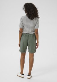 Shorts verts avec des ourlets retroussés, taille élastique, associés à un haut gris à rayures et à manches courtes. Tissu lisse et coupe décontractée.