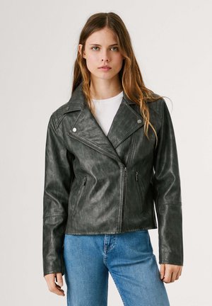 Zwarte neplederen motorjack met een brede revers, ritssluiting aan de voorkant en twee zijvakjes. Gedragen over een witte T-shirt en blauwe jeans.