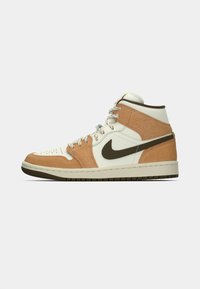 A Nike Air Jordan 1 sportcipő fehér bőrből készült alapja barna velúr kiegészítőkkel és sötétbarna Nike logóval rendelkezik, magas szárú dizájnja van, és texturált talppal bír.