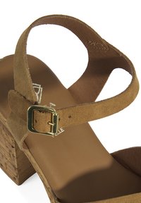 Bruine suedine platform sandaal met een chunky kurken hak, enkelband met een goudkleurige gesp en een gladde binnenvoering.