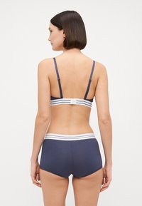 Marineblauw ondergoedset met slanke bandjes, een bijpassende tailleband met witte strepen en een gladde, matte textuur.