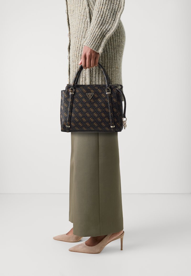 Borsa nera con motivo logo dorato, tessuto testurizzato, due manici e tracolla removibile. Abbinata a una gonna lunga oliva e tacchi beige.