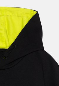 Felpa nera con fodera interna giallo brillante, dotata di coulisse e tessuto morbido, progettata con una vestibilità casual e cuciture senza soluzione di continuità.