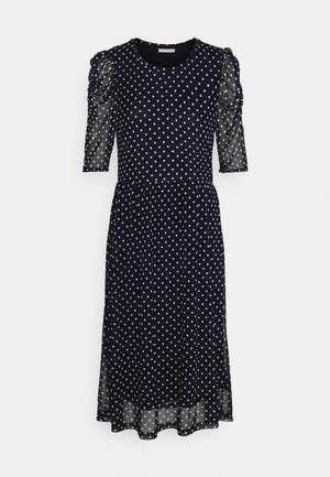 Navy blue midi dress with white polka dots, ruched sheer half sleeves, round neckline, and slightly flared skirt.