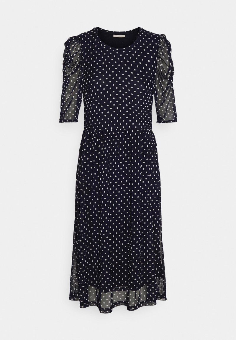 Robe midi bleu marine à pois blancs, manches mi-longues transparentes froncées, encolure ronde et jupe légèrement évasée.