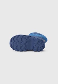 Niebieskie buty sportowe do użytku na zewnątrz z teksturowaną gumową podeszwą z zygzakowatym wzorem bieżnika. Materiał cholewki wydaje się miękki, z kontrastowym pomarańczowym akcentem.