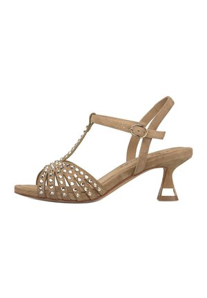 Beige Wildleder-Pumps mit mittelhohem Absatz, T-Riemen, Knöchelschnalle, offenen Zehen und silbernen Nietenverzierungen an den vorderen Riemen.