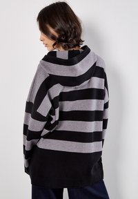 Czarna i szara bluzka z kapturem w paski, z dużym kapturem, luźnym krojem i miękką tkaniną. Długie rękawy i fason z opuszczoną linią ramion.