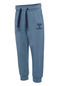 Ljusblå joggingsbyxor gjorda av mjukt tyg. Har en elastisk midja med dragsko, ribbade muddar och en logotyp framtill.