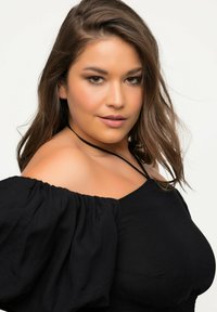Sort off-shoulder bluse med puffede ærmer og smocket bodice. Har en tynd, justerbar strop og en blød, let tekstur.