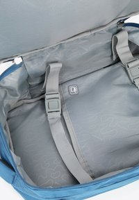 Modrý kufr uvnitř s světlými šedými popruhy a přezkami, vzorovou podšívkou a malou kapsou na karty uvnitř.