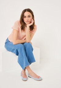 Gaiši zili zamšīgi ballet zābaciņi ar korallkrāsas lentīti, apvienoti ar svītrainu oranžs balto T-kreklu un platām denim biksēm.