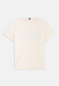 T-shirt en coton de couleur crème avec un col en V et des manches courtes. L'arrière comporte une impression de logo subtile.