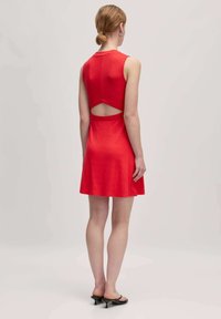 Rotes ärmelloses Kleid mit tailliertem Oberteil und ausgestelltem Rock, das ein geschnittenes Rückendesign aufweist. Hergestellt aus geripptem Stoff.