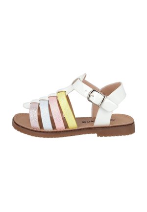 Sandalia blanca con tiras brillantes de varios colores en rosa, azul, amarillo y morado. Cuenta con una hebilla de metal y una suela plana color marrón.