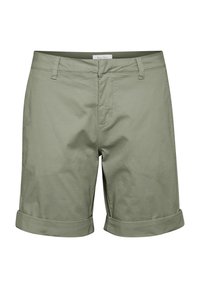 Shorts en coton vert clair avec devant plat, revers pliés et poches standard; texture lisse avec coutures visibles et étiquette de logo.