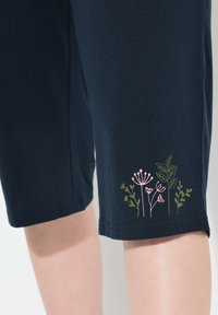 Marineblauwe katoen shorts met geborduurd bloemenontwerp in roze en groen aan de onderkant. Gladde textuur, knielange snit, casual pasvorm.