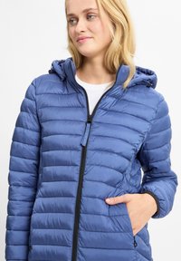 Padded hooded jacket w kolorze jasnoniebieskim, z zapięciem na zamek z przodu, teksturowanym materiałem oraz bocznymi kieszeniami. Akcenty obejmują czarny zamek.