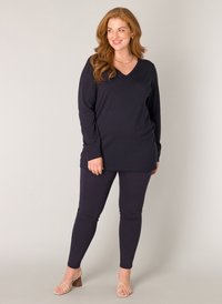 Navy lange mouwen top met een V-hals, gecombineerd met aansluitende navy leggings. Beide zijn gemaakt van een zachte stof met een gladde textuur.