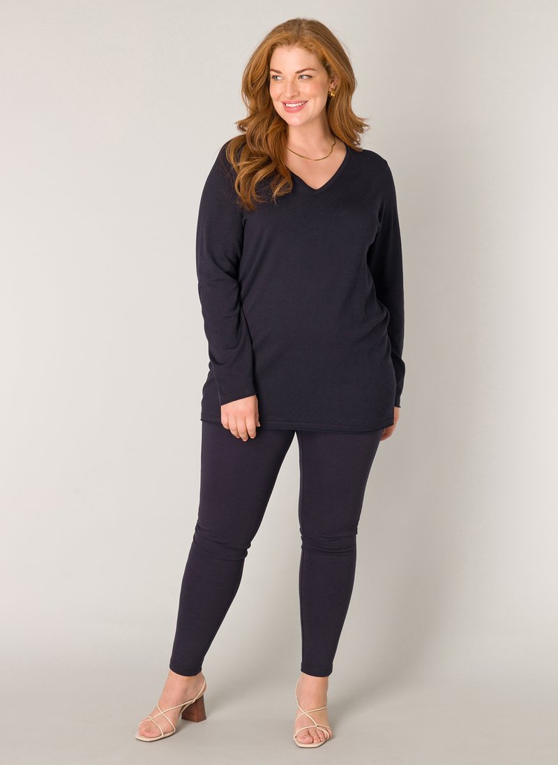 Navy lange mouwen top met een V-hals, gecombineerd met aansluitende navy leggings. Beide zijn gemaakt van een zachte stof met een gladde textuur.