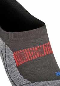 Grijze sportkous met een rood gestreept patroon, zwarte boord en een geprofileerd materiaal voor grip. Onzichtbaar ontwerp voor minimale zichtbaarheid.