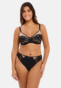 Soutien-gorge en dentelle noire et culottes assorties avec un motif en dentelle florale, des panneaux en tulle et un petit nœud décoratif au centre avant de chaque pièce.