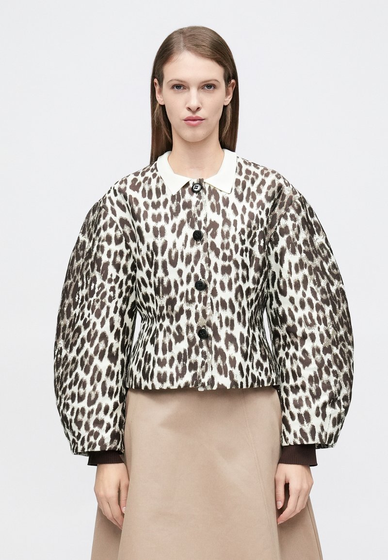 Μπουφάν με λεοπάρ σχέδιο και δομημένη εφαρμογή, που διαθέτει λευκό γιακά, μεγάλα κουμπιά και φουσκωτά μανίκια. Το υλικό φαίνεται υφασμάτινο και με σχέδιο.