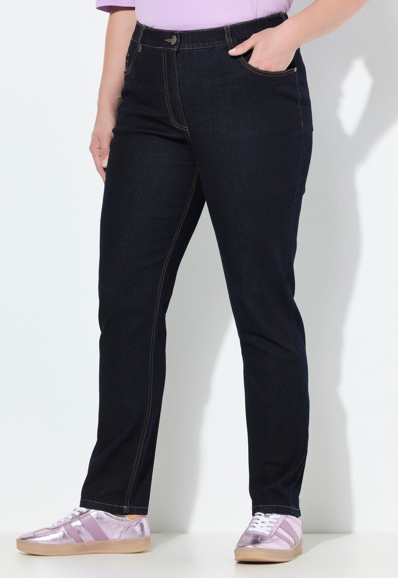 Tmavě modré džíny z denimu s kontrastním šitím, slim fit a bočními kapsami. V kombinaci se světle růžovými metalickými teniskami.