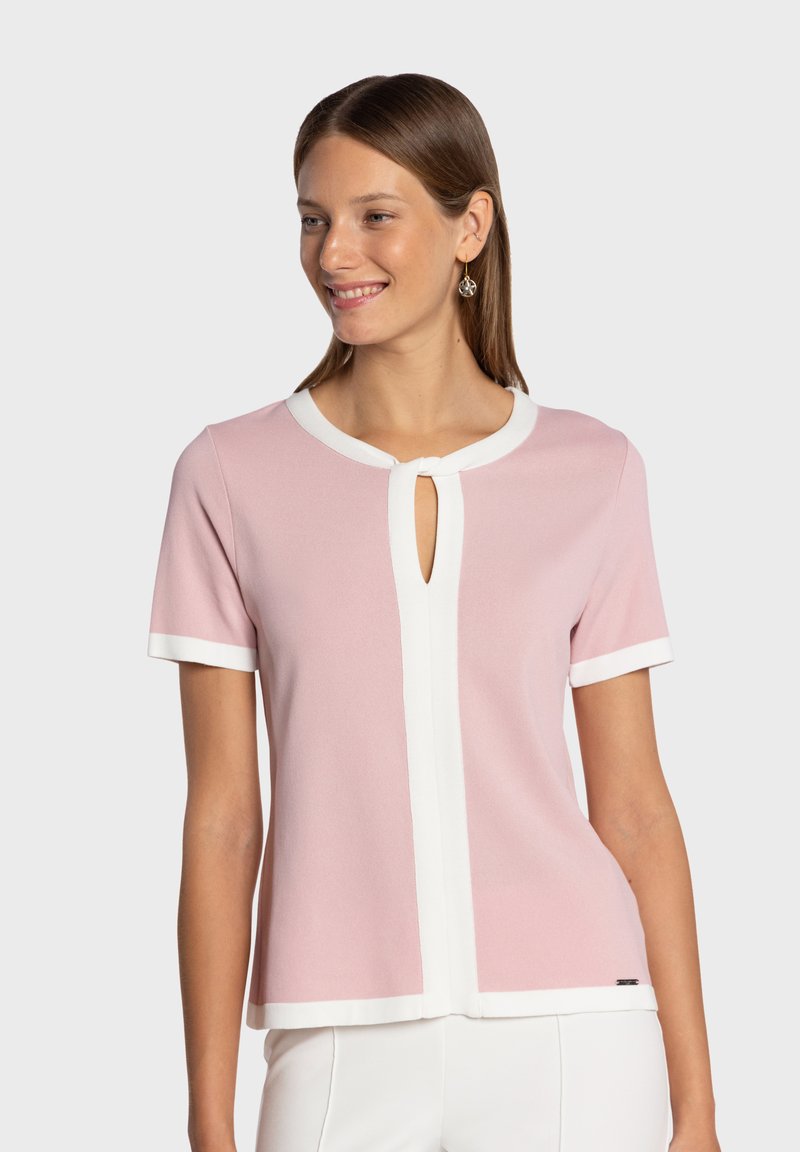 Top rosa de manga corta con ribete blanco, con un escote en forma de ojo de cerradura y textura suave. Diseño simple y limpio con un ajuste relajado.