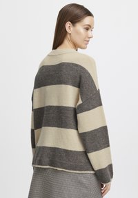 Pull à rayures beige et gris foncé avec une coupe décontractée, des manches larges et un col rond, fabriqué à partir d'un mélange de laine doux.