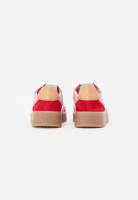 Sneaker in suede rosso e rosa con dettagli in pelle beige, dotate di una spessa suola in gomma beige e dettagli cuciti. Vista posteriore mostrata.