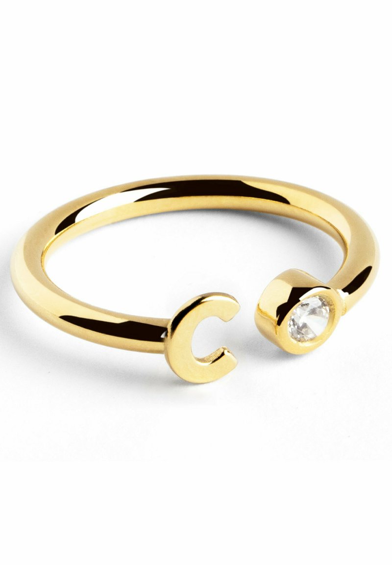 Anello placcato in oro con un design a forma di C su un'estremità e una pietra preziosa trasparente incastonata in una base arrotondata sull'altra estremità.