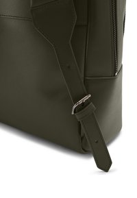 Verstellbarer dunkelgrüner Leder-Schulterriemen mit silberner Schnalle, befestigt an einer Ledertasche mit vertikalem Reißverschluss und Seitentasche.