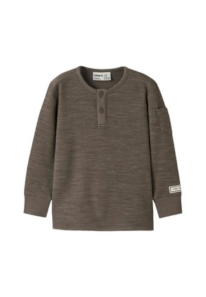 Chemise henley marron à manches longues avec deux boutons, poignets côtelés, petite poche sur la manche gauche et étiquette en tissu près du poignet.