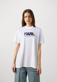 Weißes Baumwoll-T-Shirt mit kurzen Ärmeln, Rundhalsausschnitt und blauem Logo-Text "KARL LAGERFELD" auf der Vorderseite. Der Text enthält ein grafisches Akzent.
