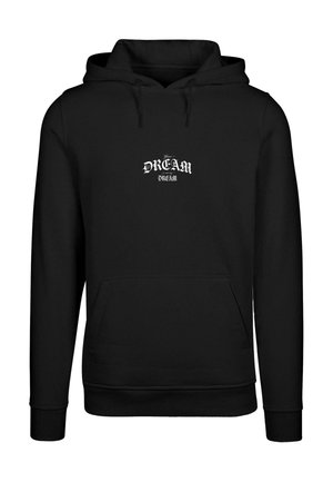 Sudadera negra con un bolsillo frontal, que presenta un diseño impreso en blanco que dice "Tu SUEÑO" y "SUEÑO" en texto estilizado. Textura de tela suave.