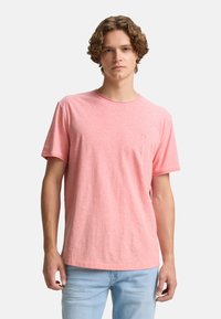 Camiseta de manga corta de color rosa claro hecha de una tela suave; presenta un escote redondo y un sutil logotipo en el pecho.